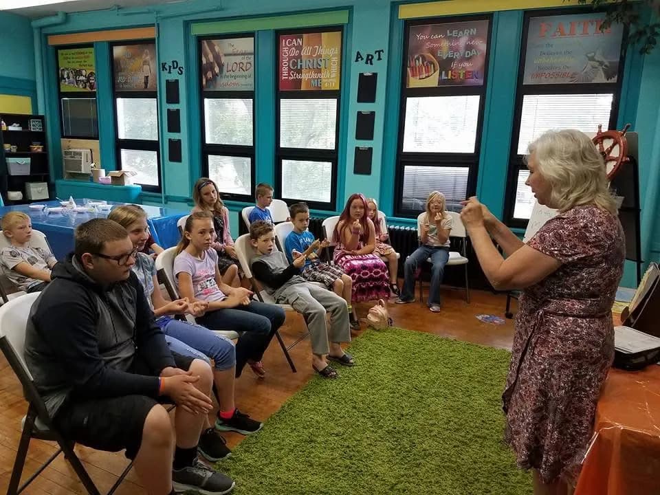 A teacher leading a lesson with children gathered on chairs around her