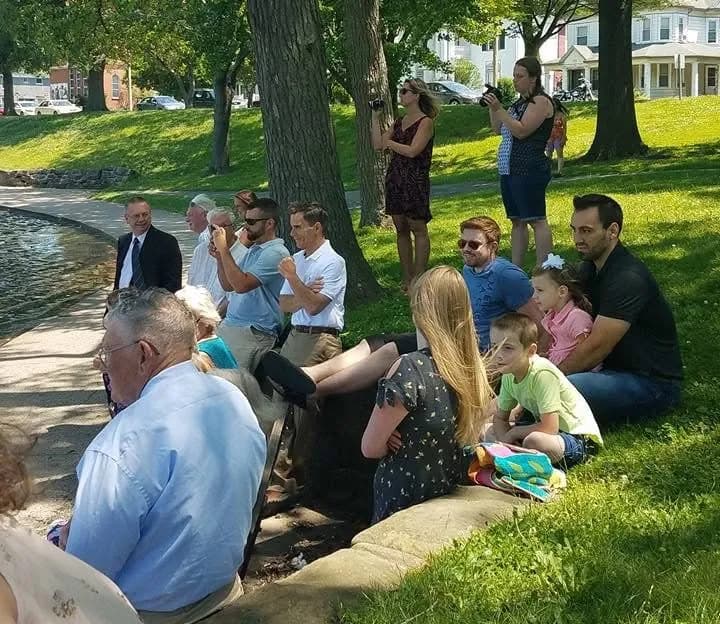 The church family seated on the grassy shore of Lake Anna for a baptism